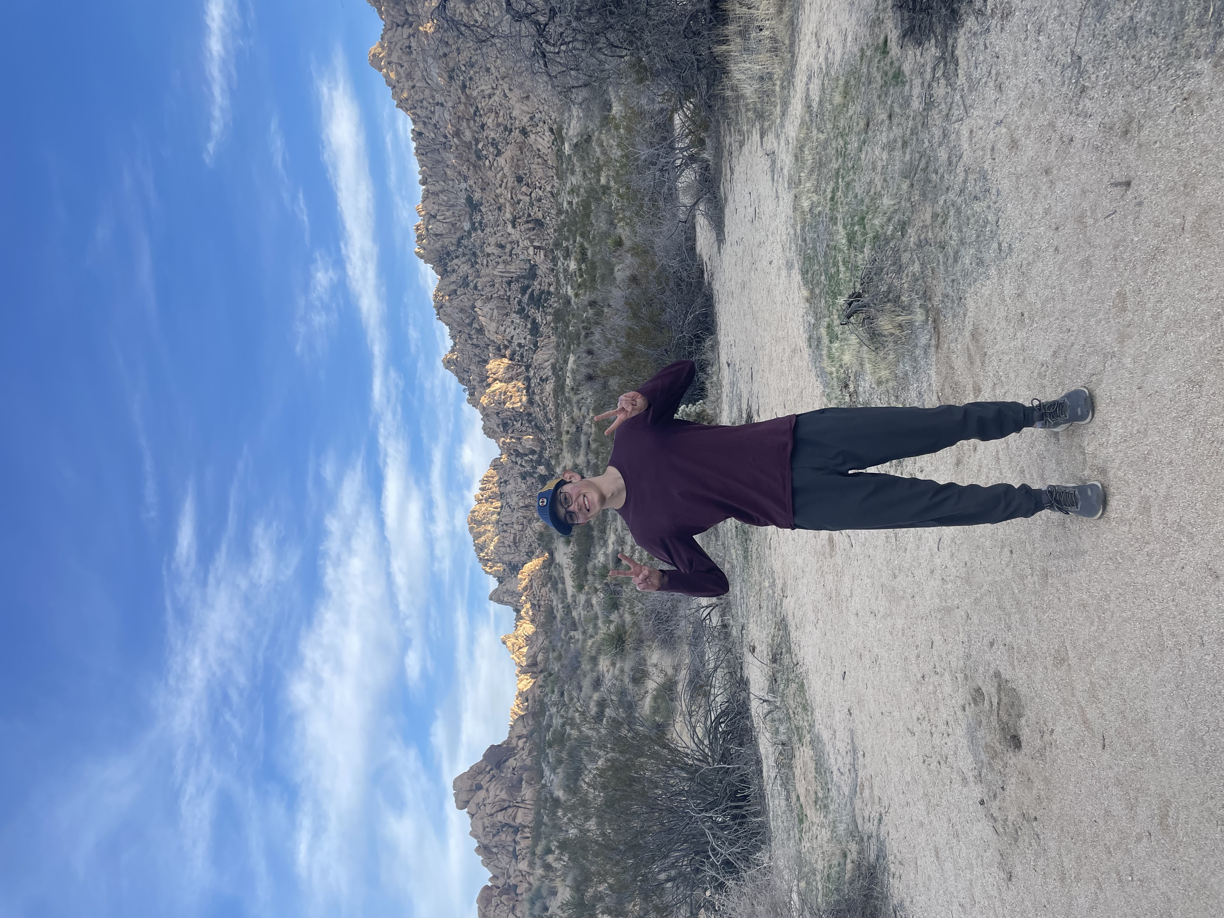 Justin making two peace signs and smiling at the camera in Joshua Tree national park.